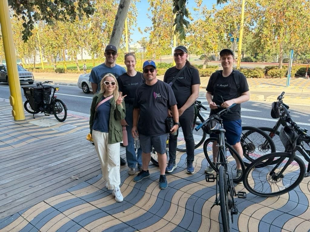 Six Arcjet teammates standing outdoors on a patterned sidewalk on a sunny day