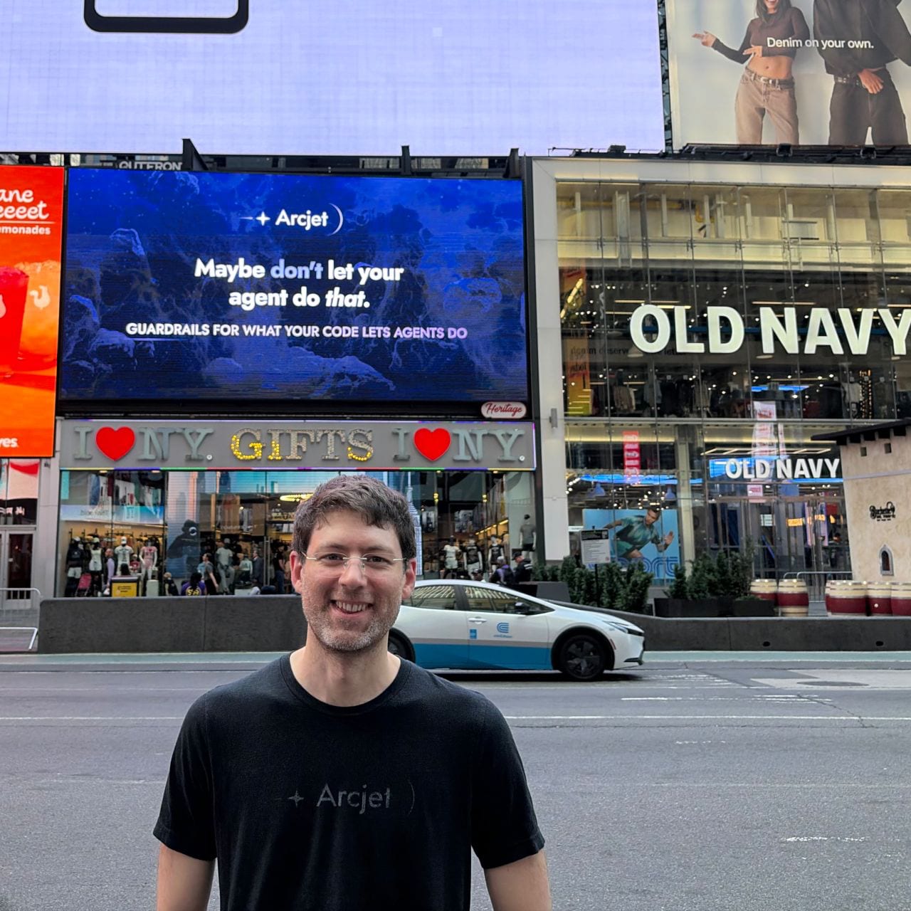 David Mytton standing in Times Square in front of an Arcjet digital billboard that reads Maybe don't let your agent do that